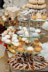 Delicious wedding reception candy bar dessert table full with cakes and sweets. Delicious & tasty decorated cupcakes at wedding reception closeup.
