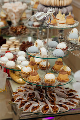 Delicious wedding reception candy bar dessert table full with cakes and sweets. Delicious & tasty decorated cupcakes at wedding reception closeup.