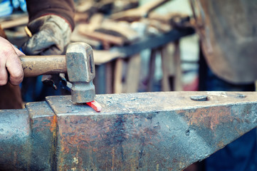Blacksmith working metal with hammer on the anvil