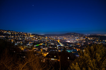 Obraz premium Germany, Stuttgart, View above skyline houses, roofs and streets iluminated by night in full moon moonlight magical atmosphere
