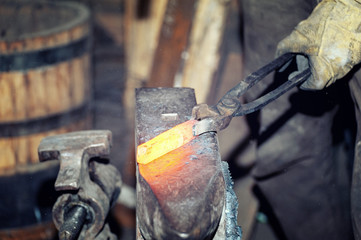 Blacksmith working metal with hammer on the anvil