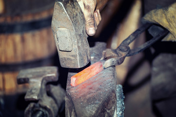 Blacksmith working metal with hammer on the anvil