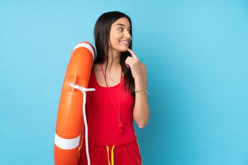 Lifeguard woman over isolated blue background with lifeguard equipment and thinking an idea while looking side