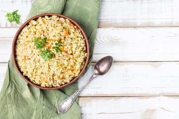 Stewed side dish of brown rice in a bowl on a green linen napkin. Traditional national cuisine. The image has a copy space