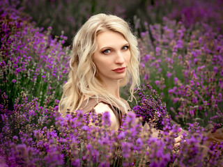beautiful blonde girl in a light flying dress in a lavender field in summer enjoying her holidays