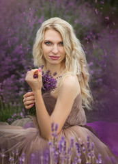 Naklejka premium beautiful blonde girl in a light flying dress in a lavender field in summer enjoying her holidays