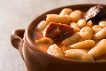 Typical Spanish fabada asturiana in crockpot on wooden table. Close up