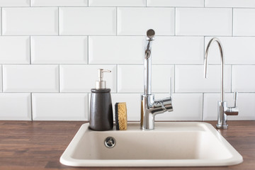 Sink with faucet in the kitchen. leanliness, water saving, washing dishes in a bright Scandinavian interior