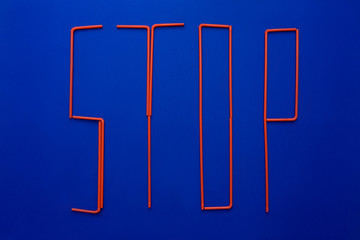 Word of stop from disposable tubes on blue background. Ocean pollution symbol.