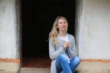  Blond girl with mini jeans resting on the porch of an old Ukrainian-style house
