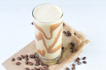 Glass of coffee and cream milkshake on white wooden background