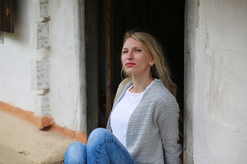  Blond girl with mini jeans resting on the porch of an old Ukrainian-style house