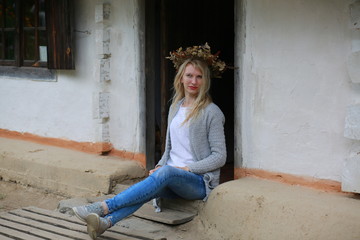  Blond girl with mini jeans resting on the porch of an old Ukrainian-style house