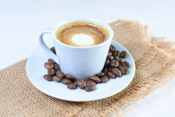 Maquiatto coffee cup with coffee beans on white wooden background
