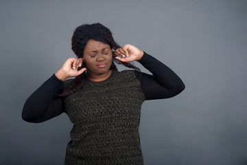 Stop making this annoying sound! Headshot of unhappy stressed out young female making worry face, plugging ears with fingers, irritated with loud noise coming from neighbours who live above her.