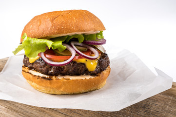Tasty homemade burger consisting of bun, cheese, salad, red onion and tomato