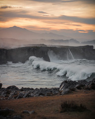 Ola rompiendo en un acantilado al atardecer 
