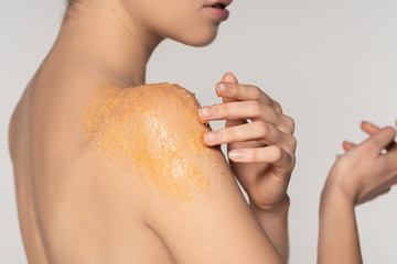 cropped view of girl applying sugar scrub on shoulder, isolated on grey
