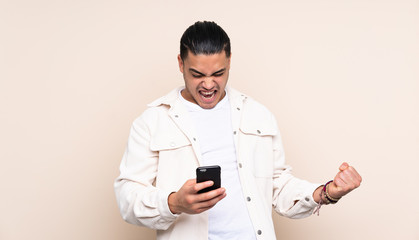 Asian handsome man over isolated background with phone in victory position