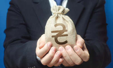 A man holds out a ukrainian hryvnia money bag. Trade, economics. Granting financing business...