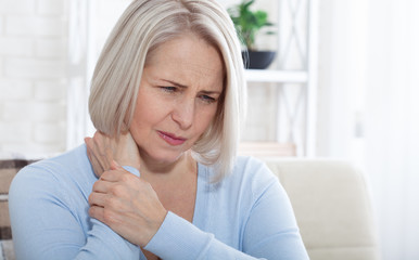 Woman with pain in her neck, medical shot at home. Concept photo with indicating location of the pain.