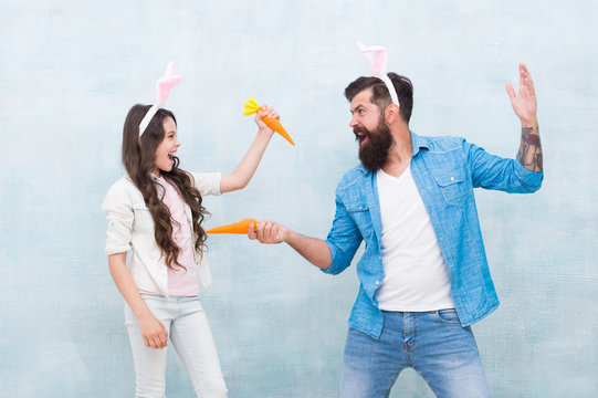 lets play together. fun and happiness. father and daughter hold carrot. spring holiday party. small kid girl and dad in rabbit costume. healthy food. easter carrot fight. happy family wear bunny ears