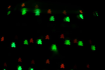 Fototapeta na wymiar Bokeh in the form of bears of red and green colors on a dark background