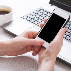 A woman holds smartphone white phone in the workplace in the room. Woman using a mobile phone for work.