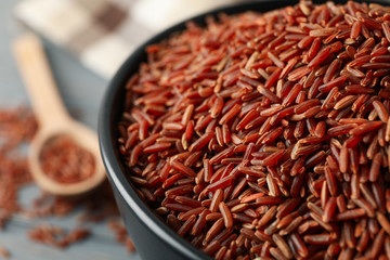 Bowl with rice, towel and spoon on wooden background, close up