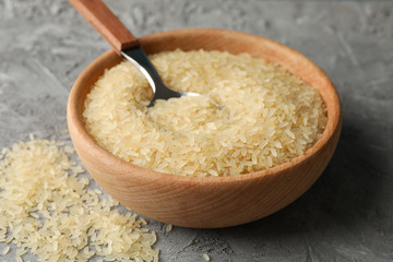 Bowl with rice and spoon on grey background, close up