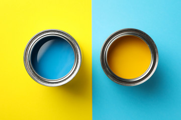 Cans of blue and yellow paint on two tone background, top view