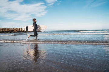 Surfer entering into the water with his surfboard.