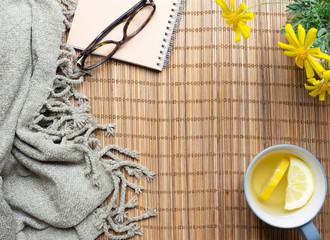 Top view of Green tea with lemon ,book,glasses ,yellow flower and cozy blanket on the wood mat...