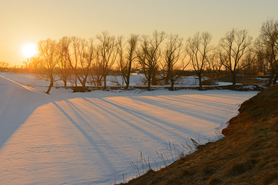 Evening spring landscape with melting snow and long shadows