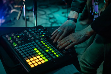 A closeup and high angle view on the hands of an electronic music deejay using a modern mixing...