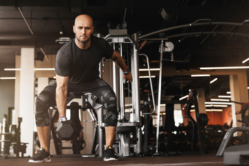 Fototapeta na wymiar Caucasian athletic man bodybuilder doing exercises with dumbbell in gym