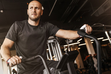 Fototapeta na wymiar Fitness male using air bike for cardio workout at gym