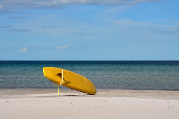 Yellow surfboard on a sandy sea beach