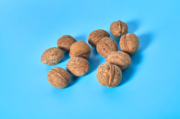 Scattered whole ripe walnuts on blue background