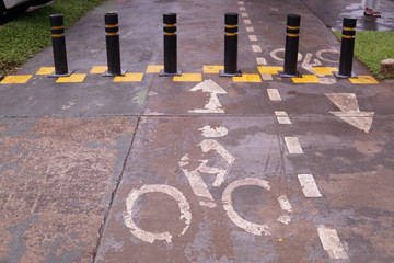 Restrictive posts between the pedestrian sidewalk and the road. poles of yellow-black color, striped with bicycle icon on the road