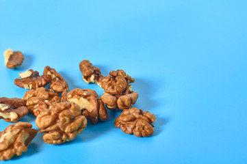 Fototapeta na wymiar Scattered pieces of pulp of walnut on blue background. Copy space