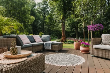 Tuinposter Classy furniture on wooden terrace in green beautiful garden © Photographee.eu