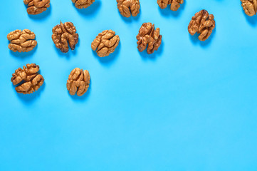 Scattered halves of pulp of walnut on blue background. Copy space. Top view