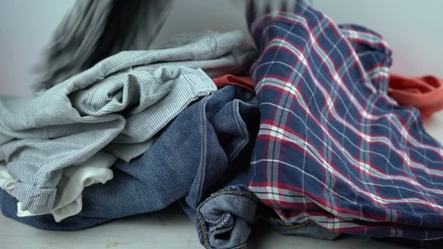 Jeans, pajama, shirts falling on the table in apile. Clothes for donation or dirty laundry concept