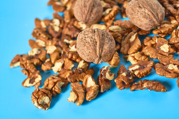 Heap of halves of pulp and whole walnut on blue background