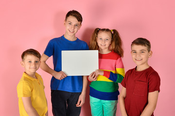 Four children are holding a poster in their hand with an empty place, on a pink background.