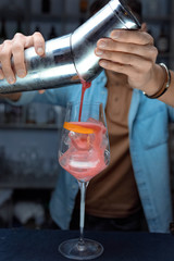 bartender pouring a cocktail into glass