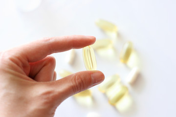 Womens hand is holding a pill. Tablets and pills laying on table. Background for pharmacology....