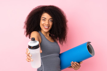 Young african american sport woman isolated on pink background with sports water bottle and with a...
