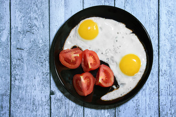 fried eggs on a black plate.tomatoes in slices.good nutrition.diet